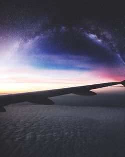 Cropped image of airplane over sea at night