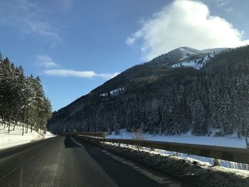 Road by mountain against sky during winter