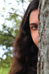 Close-up portrait of woman against tree trunk