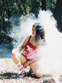 Full length of woman sitting against waterfall