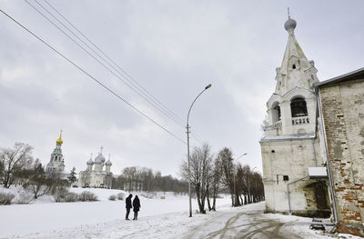 People by building against sky during winter