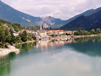 Scenic view of lake by buildings and mountains against sky