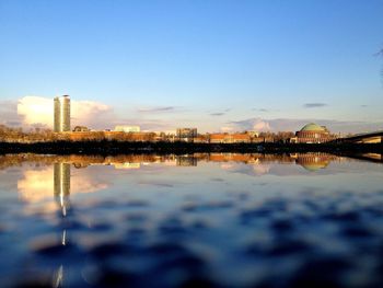 Reflection of buildings in lake against blue sky