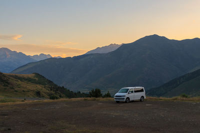 White van parked in parking lot between mountains