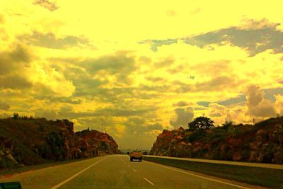 Road passing through landscape against cloudy sky