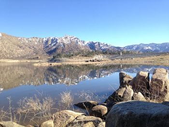 Scenic view of lake and mountains against clear blue sky