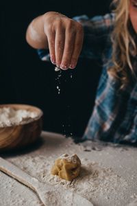 Child's hand adding just a little bit of flour on cookie dough
