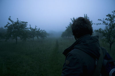 Rear view of man against trees on foggy day