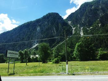 Road by trees and mountains against sky