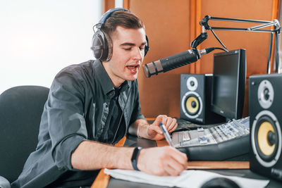 Talks and uses mic. young man is indoors in the radio studio is busy by broadcast.