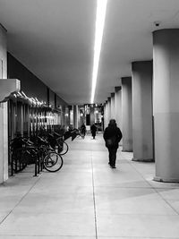 Rear view of woman walking in illuminated corridor