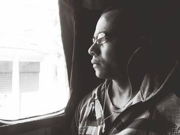 Close-up of man listening music while looking through window