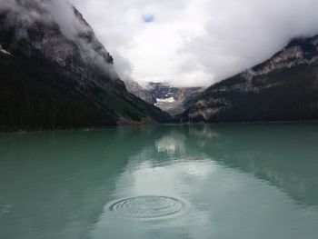 Scenic view of clouds at rocky mountains by lake