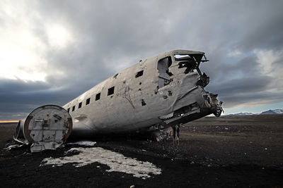 Abandoned airplane on airport runway against sky