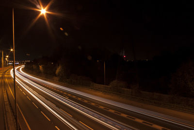 Light trails on road against sky at night