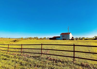 Fence on field against blue sky