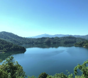 Scenic view of lake and mountains against clear blue sky