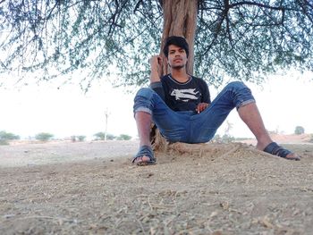 Full length portrait of young man in park against sky