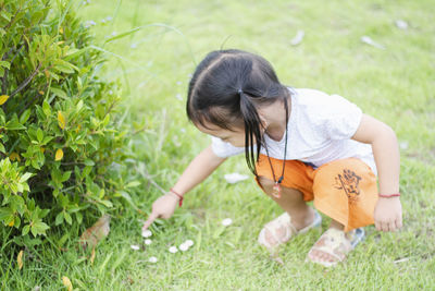 Side view of young woman sitting on grassy field