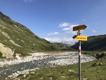 Information sign by road against sky