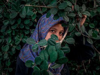 Portrait of young woman with leaves in plant