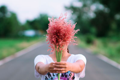 Close-up of woman holding flower on road