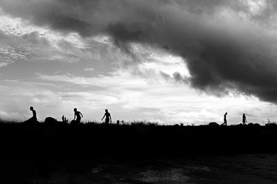 Silhouette people by sea against sky during sunset