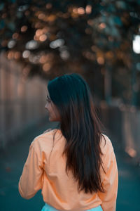 Rear view of woman looking away while standing outdoors