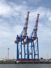 Low angle view of cranes at harbour site