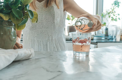 Midsection of woman standing on table at home