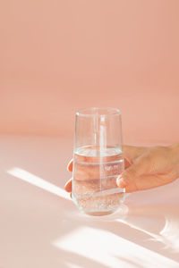 Transparent glass on a peach background in the sunlight gives