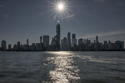 Sea by modern buildings in city against sky