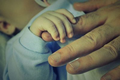 Midsection of baby holding father finger