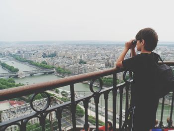 Rear view of man photographing cityscape against clear sky