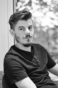 Portrait of man sitting by window at home