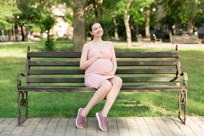 Portrait of woman sitting on bench in park