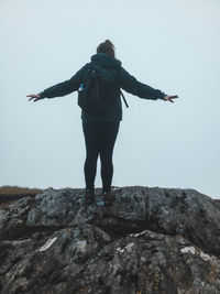 Rear view of woman standing on rock against sea