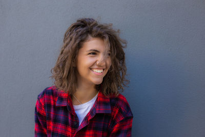 Portrait of young happy sensual woman with curly hair in red shirt on grey background