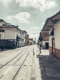 Empty road amidst buildings in city against sky