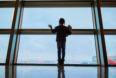 Rear view of man standing on window