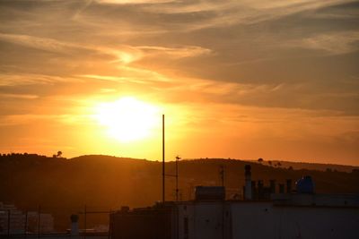 Silhouette built structures against sky during sunset