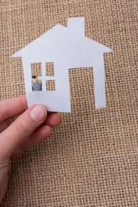Cropped hand holding paper model home against jute