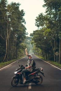 Man riding motorcycle on road amidst trees