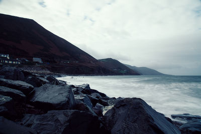 Scenic view of sea by mountains against sky