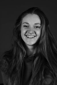 Portrait of smiling young woman against black background