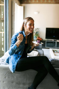 Happy young woman eating a healthy dessert at home