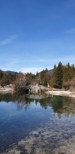 Scenic view of lake by wooden building against blue sky