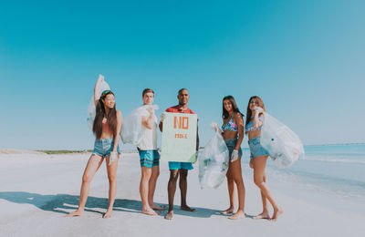 Portrait of activist holding plastic bags while standing at beach