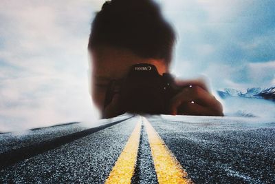 Rear view of a man photographing on road