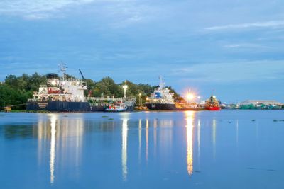 Illuminated harbor by sea against sky